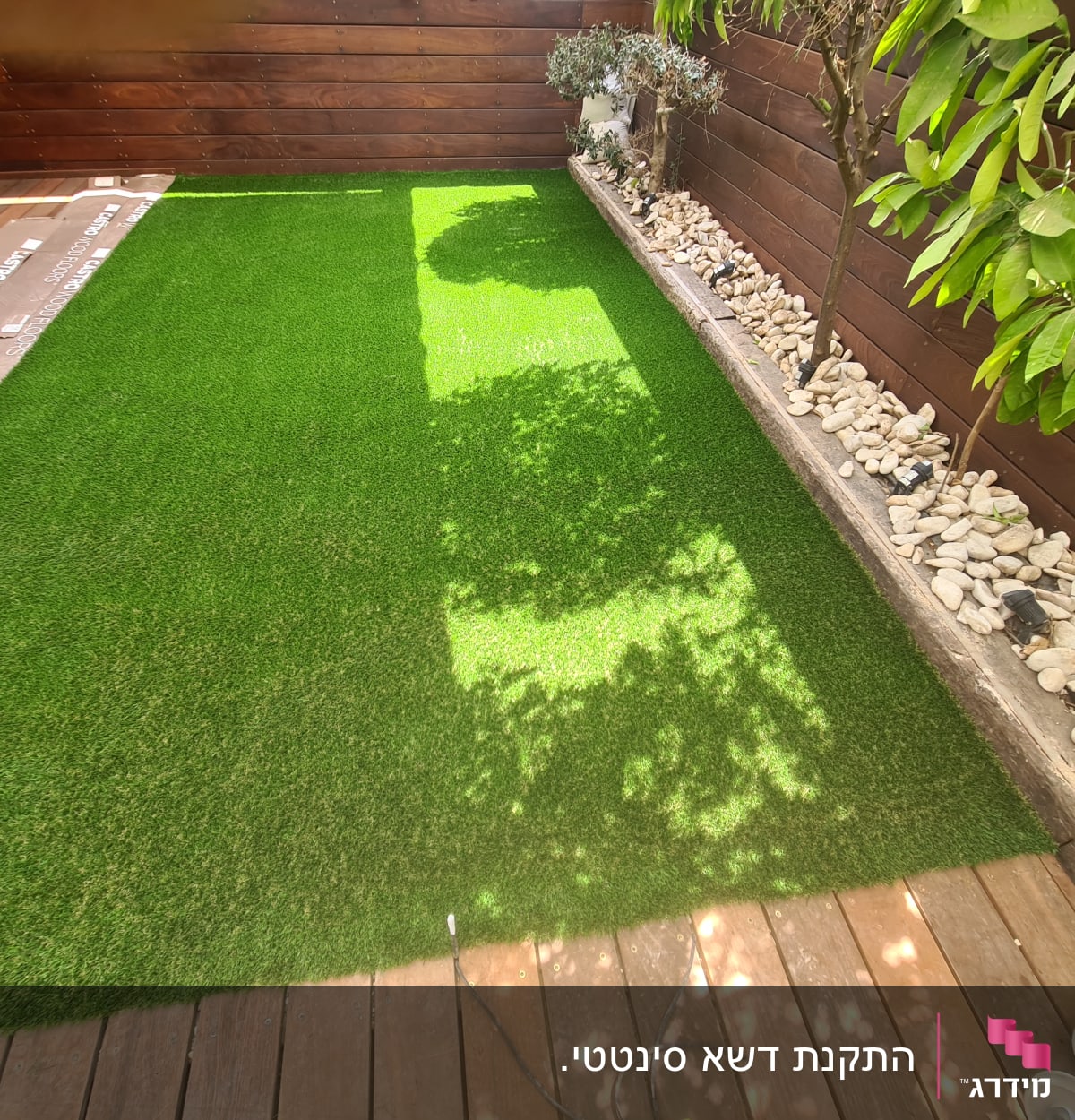 דשא סינתטי, עצים קטנים, אבנים לבנות, גינה קטנה